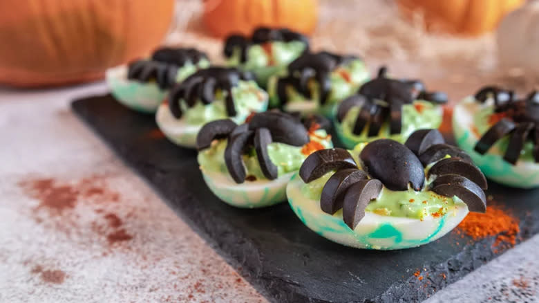 Green deviled eggs with olive garnish