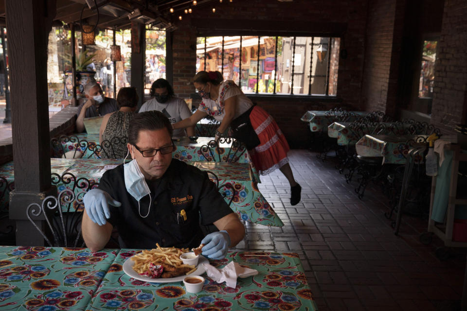 Everardo Gallegos, one of managers at El Paseo Inn Mexican restaurant on Olvera Street, eats his lunch at the restaurant with his protective gloves on in Los Angeles, Friday, June 4, 2021. Olvera Street has long been a thriving tourist destination and a symbol of the state's early ties to Mexico. The location of where settlers established a farming community in 1781 as El Pueblo de Los Angeles, its historic buildings were restored and rebuilt as a traditional Mexican marketplace in 1930s. As Latinos in California have experienced disproportionately worse outcomes from COVID-19, so too has Olvera Street. (AP Photo/Jae C. Hong)