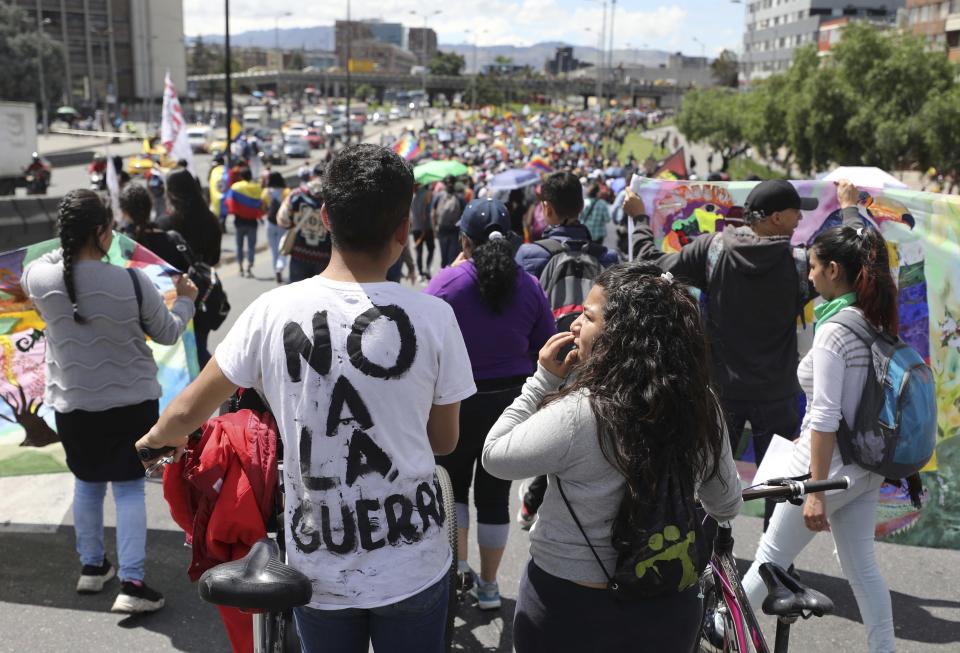 Demonstrators, one wearing a t-shirt with text that reads in Spanish "No to war," march during a national strike in Bogota, Colombia, Wednesday, Dec. 4, 2019. Colombia’s recent wave of demonstrations began with a massive strike on Nov. 21 that drew an estimated 250,000 people to the streets. Protests have continued in the days since but at a much smaller scale. (AP Photo/Fernando Vergara)