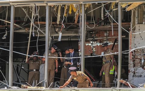 Sri Lankan police officers inspect the Shangri-La hotel in Colombo following the explosion - Credit: Chamila Karunarathne/AP