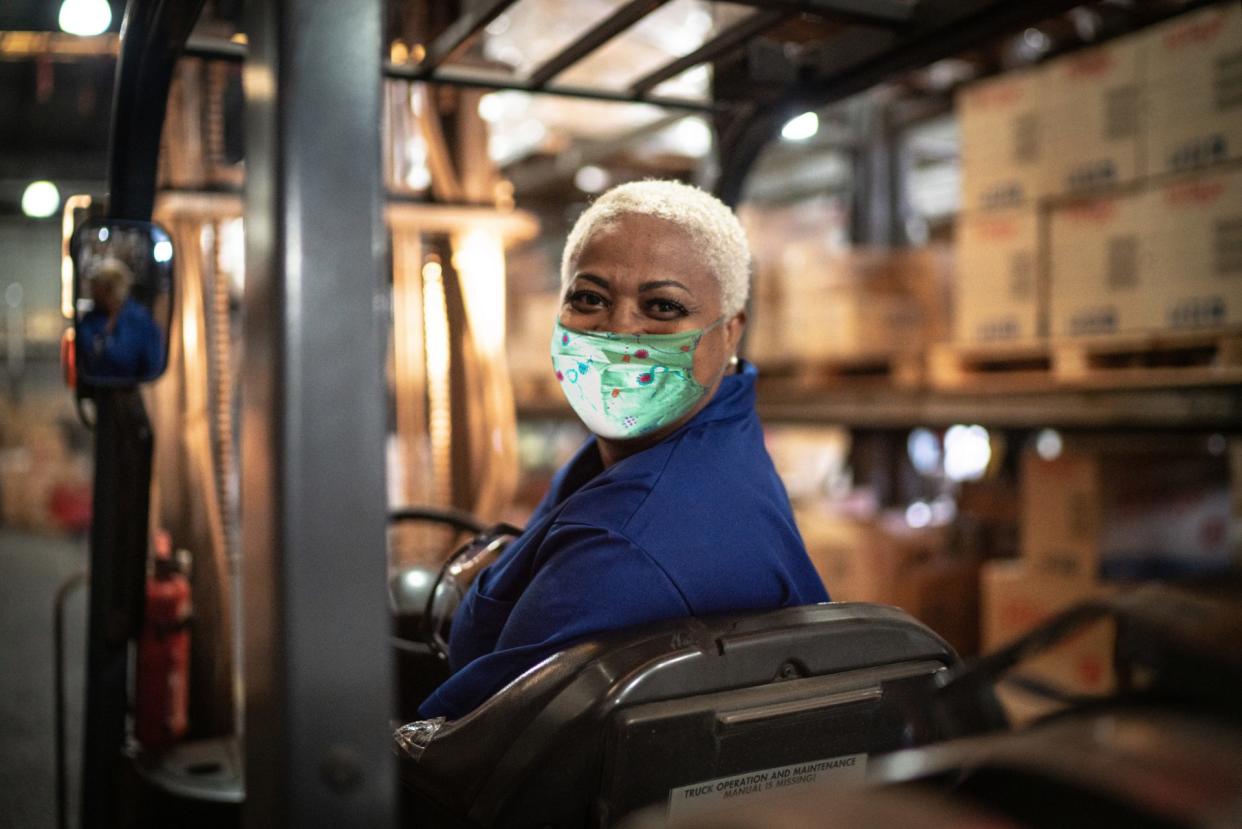 Portrait of female worker driving forklift in warehouse.