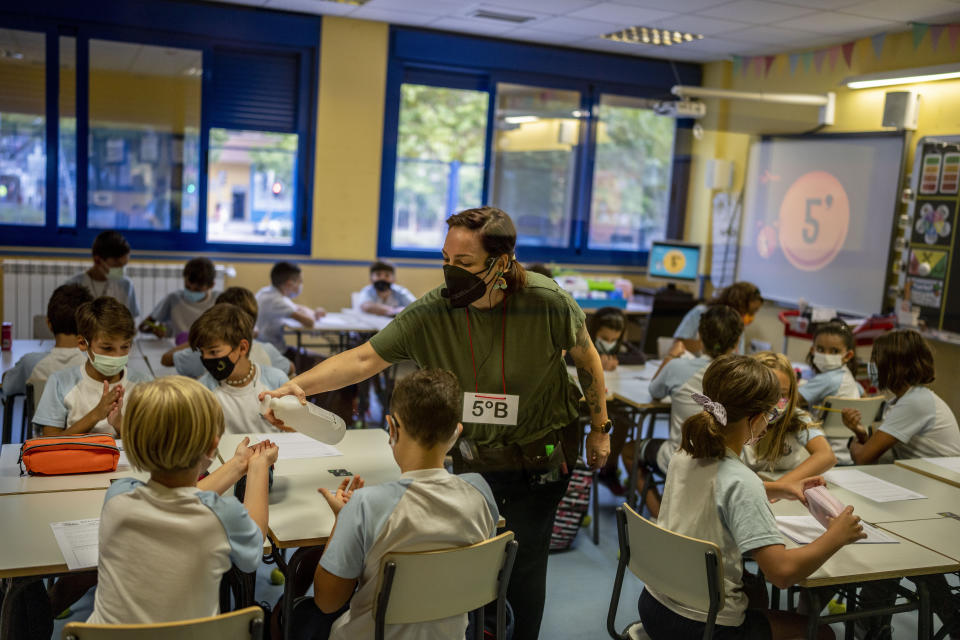 A teacher wearing a face mask to protect against the spread of coronavirus administers a disinfectant gel to a pupil at Maestro Padilla school as the new school year begins, in Madrid, Spain, Tuesday, Sept. 7, 2021. Around 8 million children in Spain are set to start the new school year. (AP Photo/Manu Fernandez)