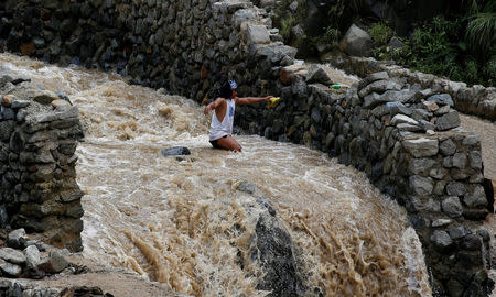 A local miner wades through water as he walks down from a mountain in Benguet a day after Typhoon Haima struck northern Philippines, October 21, 2016. REUTERS/Erik De Castro