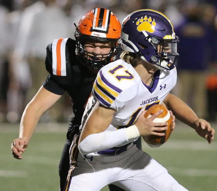 Hoover defensive end Drew Logan closes in on Jackson quarterback Hunter Geissinger during an Oct. 22, 2021 high school football game North Canton&#39;s Memorial Stadium.