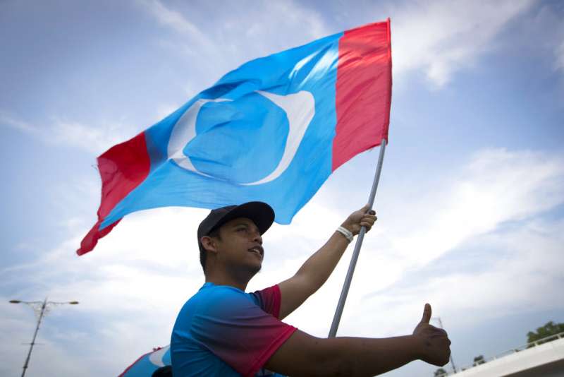 2018年5月10日，馬來西亞選舉落幕，希望聯盟首度執政，民眾揮舞希盟之一的「人民公正黨」黨旗。（AP）