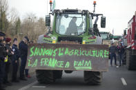 Police forces watch a farmerdriving his tractor with inscription "Save farming, France is hungry" on a highway, Monday, Jan. 29, 2024 in Argenteuil, north of Paris. Protesting farmers were encircling Paris with tractor barricades and drive-slows on Monday, using their lumbering vehicles to block highways leading to France's capital to pressure the government over the future of their industry, which has been shaken by repercussions of the Ukraine war. (AP Photo/Christophe Ena)