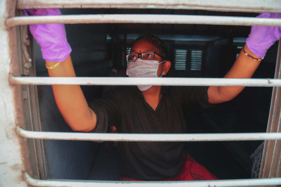 An Indian passenger wearing face mask and gloves as a precaution against COVID-19 opens glass window of a train compartment at Secunderabad Railway Station in Hyderabad, India, Saturday, March 21, 2020. For most people, the new coronavirus causes only mild or moderate symptoms. For some it can cause more severe illness. (AP Photo/Mahesh Kumar A.)