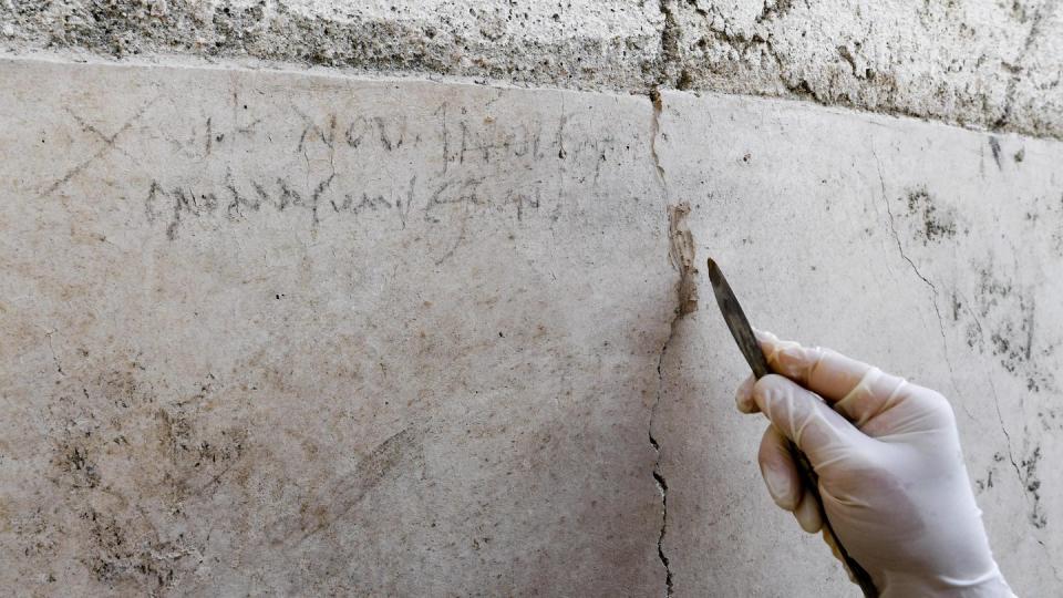 Ein Archäologe zeigt an einer Mauer in Pompeji die Kohle-Inschrift, die auf die Eruption des Vesuv im Jahr 79 verweist. Foto: Ciro Fusco/ANSA/AP