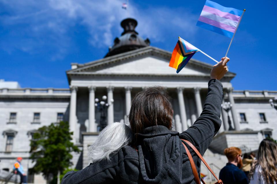 LGBTQ+ supporters raise flags representing the LGBTQ+ and transgender communities outside of the S.C. Statehouse on Wednesday, March 29, 2023. 