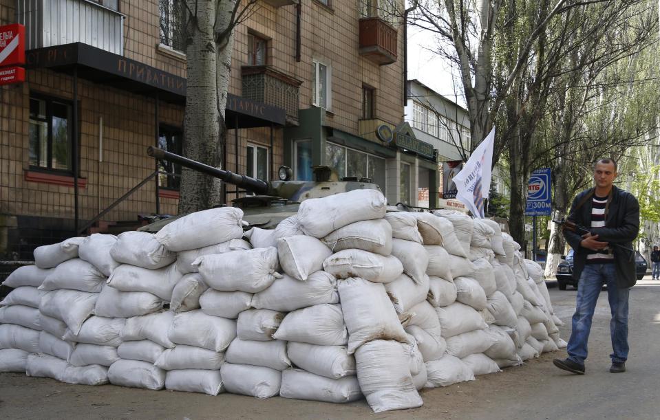 Un individuo armado pro ruso patrulla una calle en el centro de Sloviansk, en el este de Ucrania, el miércoles 23 de abril de 2014. El ministro del Interior dijo el jueves que la policía desalojó a manifestantes pro rusos que ocuparon durante una semana el Ayuntamiento en la ciudad de Mariupol, en el sureste de Ucrania. (AP Foto/Sergei Grits)