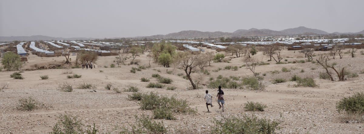 Two boys cross the rugged landscape around the Aboutengue refugee camp.<span class="copyright">Nicolò Filippo Rosso</span>