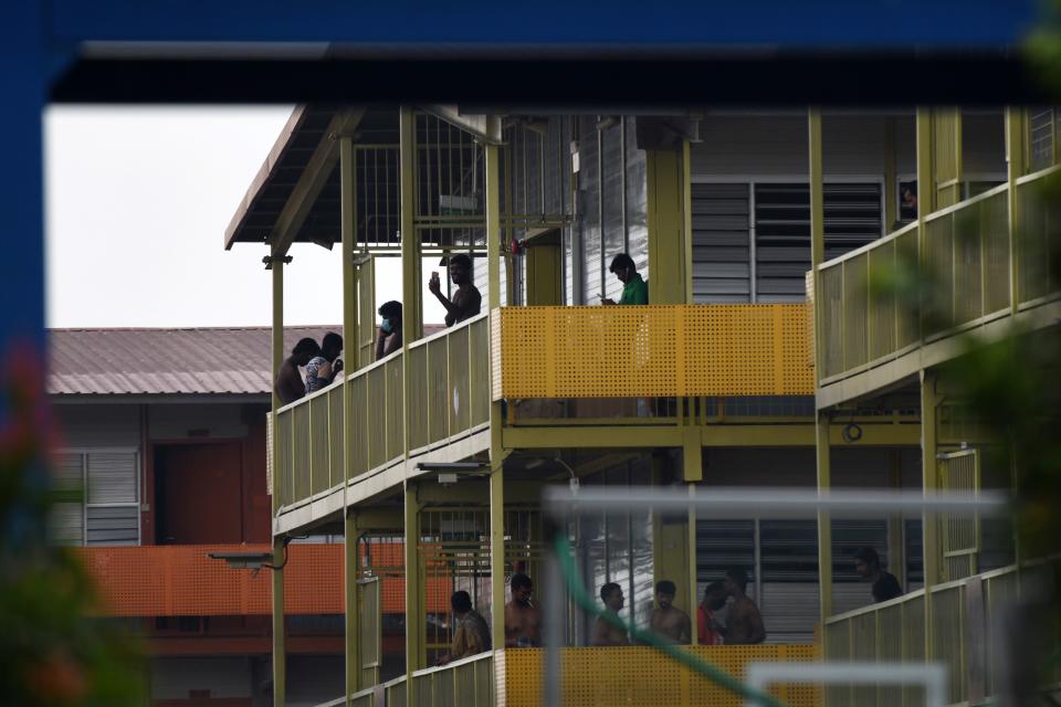 Foreign workers stand along the corridor of their rooms at the S11 Dormitory @ Punggol, where there are 62 cases of individuals with the COVID-19 novel coronavirus, in Singapore on April 6, 2020. (Photo by Roslan RAHMAN / AFP) (Photo by ROSLAN RAHMAN/AFP via Getty Images)