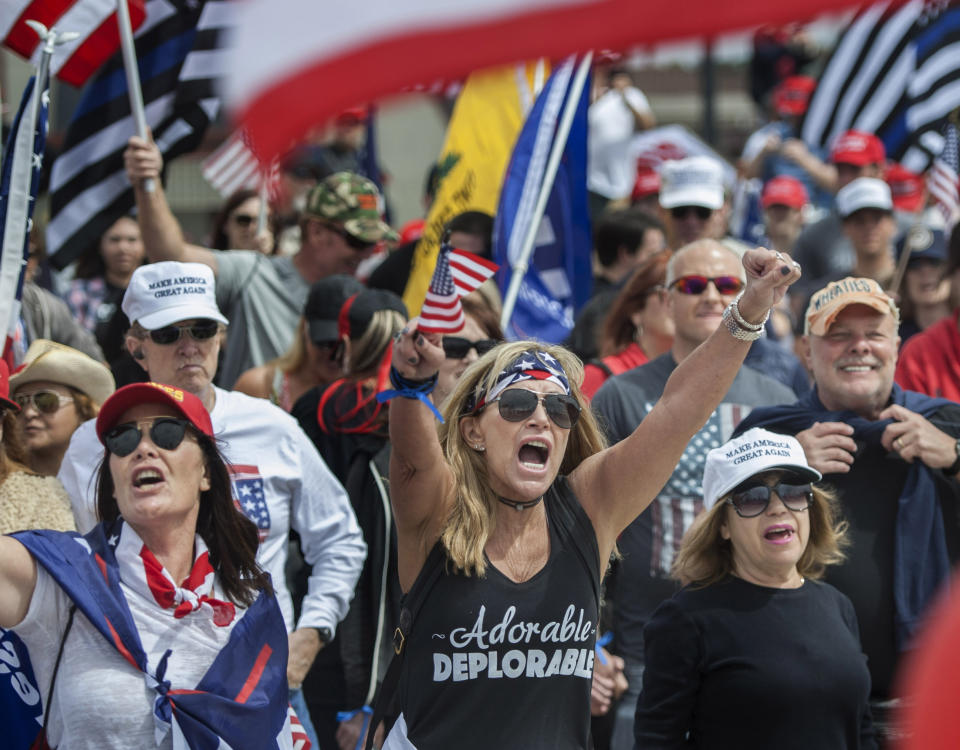 Wearing her "Adorable Deplorable" tee, Deanne Payn, center, with Sheila Ponce, left, take part in a pro-President Donald Trump rally in Huntington Beach, Calif., on Saturday, March 25, 2017. The women are retired Sheriff deputies. A scuffle later broke out between pro-Trump supporters and counter-protesters. (Mindy Schauer/The Orange County Register via AP)