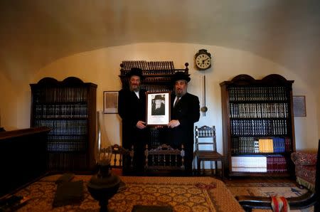 The two sons of a leading Hasidic rabbi hold up their father Rabbi Eliezer Ehrenreich's photo in the newly-restored rabbi house in the village of Mad, Hungary, July 21, 2016. Picture taken July 21, 2016. REUTERS/Laszlo Balogh