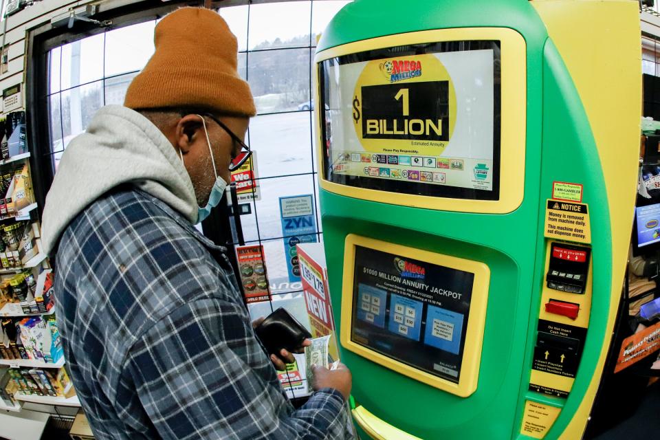 A patron, who did not want to give his name, uses the lottery ticket vending kiosk at a Smoker Friendly store to purchase tickets for the Mega Millions lottery drawing on Jan. 22, 2021, in Cranberry Township, Pa.