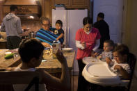 CORRECTS NAME TO SASHA NUNEZ FROM ARACELI NUNEZ - In this Thursday, Sept. 6, 2018, photo, Lilia Coyt, center left, and Coyt's daughter-in-law, Sasha Nunez, feed babies in their four-bedroom home, where three generations and 15 members of the family are jammed into, in Salinas, Calif. Few cities exemplify California's housing crisis better than Salinas, an hour's drive from Silicon Valley and surrounded by farm fields. It's one of America's most unaffordable places to live, and many residents believe politicians lack a grip on the reality of the region's housing crisis. (AP Photo/Jae C. Hong)