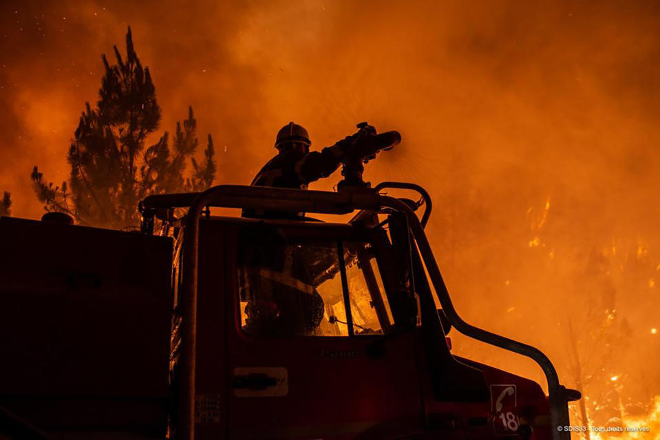 This photo provided by the fire brigade of the Gironde region SDIS 33, (Departmental fire and rescue service 33) shows firefighters tackling a blaze near Saint-Magne, south of Bordeaux, southwestern France, Wednesday, Aug. 10, 2022. (SDIS 33 via AP)