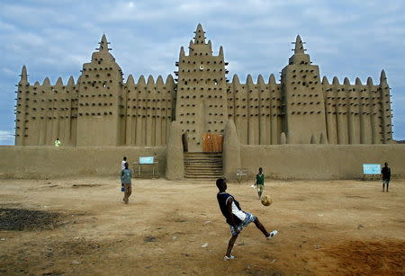 Malian youths play soccer in front of the Great Mosque in Djenne, Mali August 10, 2003. REUTERS/Yves Herman