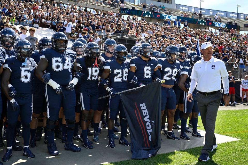 UConn head coach Jim Mora, right, stands with his team before the start of an NCAA college football game against CCSU at Pratt & Whitney Stadium at Rentschler Field in East Hartford, Conn., Saturday, Sept. 3, 2022. (Jessica Hill/Hartford Courant via AP)