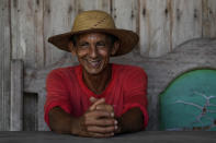 Small farmer Edison Cesar de Oliveira, known as Duduca, smiles on the porch of his house at the Colonia Mondrongo, in the rural area of the Rio Branco, Acre state, Brazil, Monday, May 22, 2023. The son of a subsistence rubber tapper from Acre, his family lives in a small wooden home that he built himself. (AP Photo/Eraldo Peres)