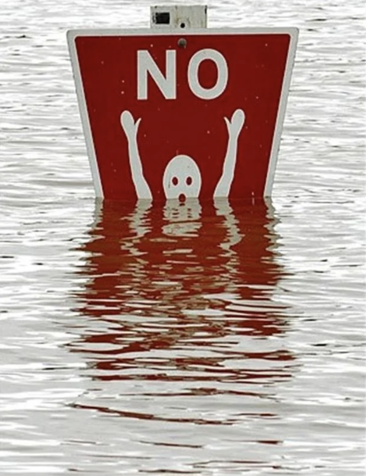 Sign with "NO" above a skull and two hands raised above water, indicating danger or no swimming
