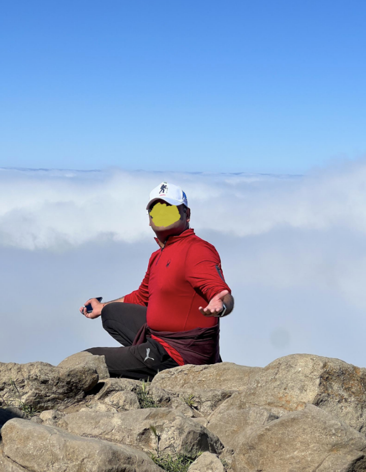 A man posing at the top of a cliff for a photo