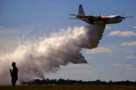 FILE PHOTO: A television reporter stands in front of the Large Air Tanker C-130 Hercules, also known as ‘Thor’, as it drops a load of around 15,000 litres during a display by the Rural Fire Service ahead of the bushfire season at RAAF Base Richmond in