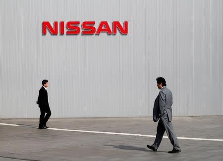 Men walk past a Nissan Motor Co logo at the company's global headquarters in Yokohama, south of Tokyo February 9, 2011.REUTERS/Toru Hanai/File Photo