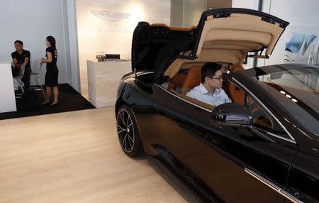 Sales Manager Raymond Liu opens the hood of an Aston Martin Vanquish at their showroom in Singapore August 1, 2014. REUTERS/Edgar Su