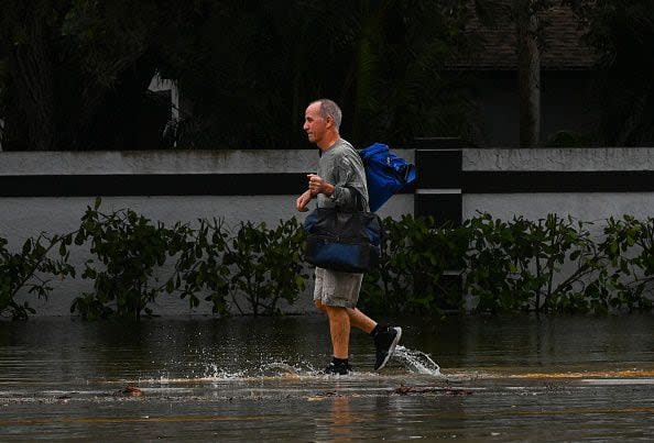 A man carrying personal belongings walks in a flooded street after Hurricane Nicoles landfall, in Vero Beach, Florida, on November 10, 2022. - Tropical Storm Nicole slowed after making landfall in the US state of Florida, meteorologists said Thursday. (Photo by Eva Marie UZCATEGUI / AFP) (Photo by EVA MARIE UZCATEGUI/AFP via Getty Images)