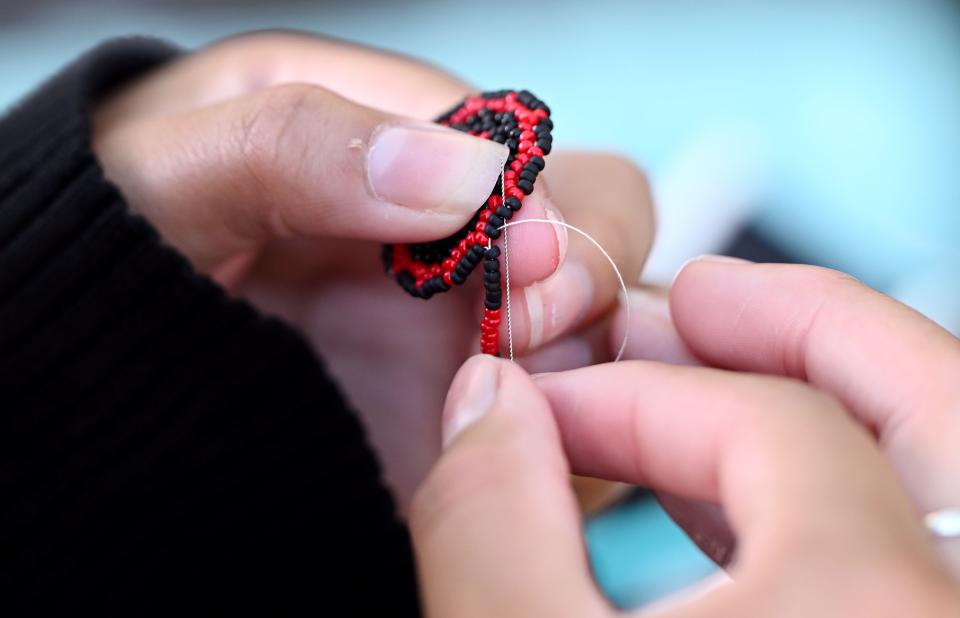 Brenda Camarena makes an earring while sitting at her craft booth at Utah Native Market Days at Thanksgiving Point in Lehi on Friday, Aug. 11, 2023. All proceeds are going to native student scholarships. There was hoop dancing, food and crafts. | Scott G Winterton, Deseret News