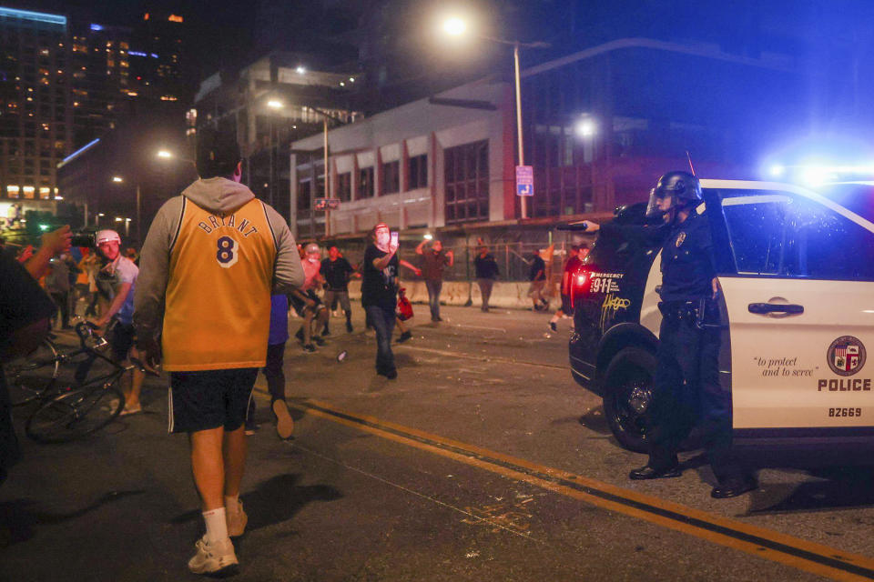 Los Angeles Lakers fans celebrate outside of Staples Center as Los Angeles Police Department officers try to disperse them, Sunday, Oct. 11, 2020, in Los Angeles, after the Lakers defeated the Miami Heat in Game 6 of basketball's NBA Finals to win the championship. (AP Photo/Christian Monterrosa)