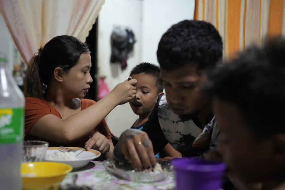 Hyancinth Charm Garing, left, feeds their son during dinner in their home in a new community for victims of super Typhoon Haiyan in Tacloban, central Philippines on Wednesday, Oct. 26, 2022. Garing and his family settled at a relocation site three years ago after their village was wiped out when the super typhoon struck in 2013, killing six family members and his year-old daughter. (AP Photo/Aaron Favila)