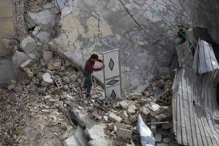 A man inspects a door amidst rubble of damaged buildings in the northern Syrian city of al-Bab, Syria March 13, 2017. REUTERS/Khalil Ashawi