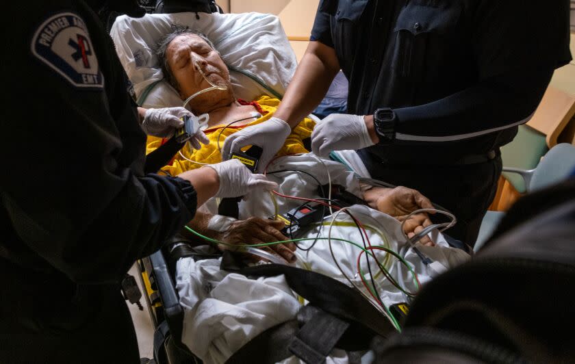 Los Angeles, CA - March 23: EMT's Meagan Parker, left, and Daniel Avena, right, buckle Ernesto Chavez, middle, onto a gurney. Chavez is a patient at MLK Community Hospital on Thursday, March 23, 2023, in Los Angeles, CA. He is being transferred. (Francine Orr / Los Angeles Times)