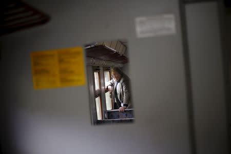 A passenger is reflected in a mirror as he looks out of a window on a train traveling towards Velingrad railway station, Bulgaria April 28, 2015. REUTERS/Stoyan Nenov