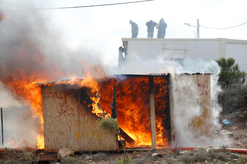 Protesters stand atop a roof as a shed burns during an eviction by Israeli police of residents from the Israeli settler outpost of Amona.