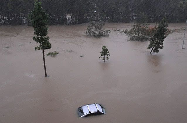 A car sits in flood waters outside the Robina Hospital on the Gold Coast. Picture: Dave Hunt/AAP