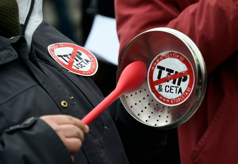 A demonstrator holds a lid with a sticker reading "TTIP & CETA" crossed during a protest against the EU-Canada Comprehensive Economic and Trade Agreement (CETA) at European Union Commission headquarters in Brussels