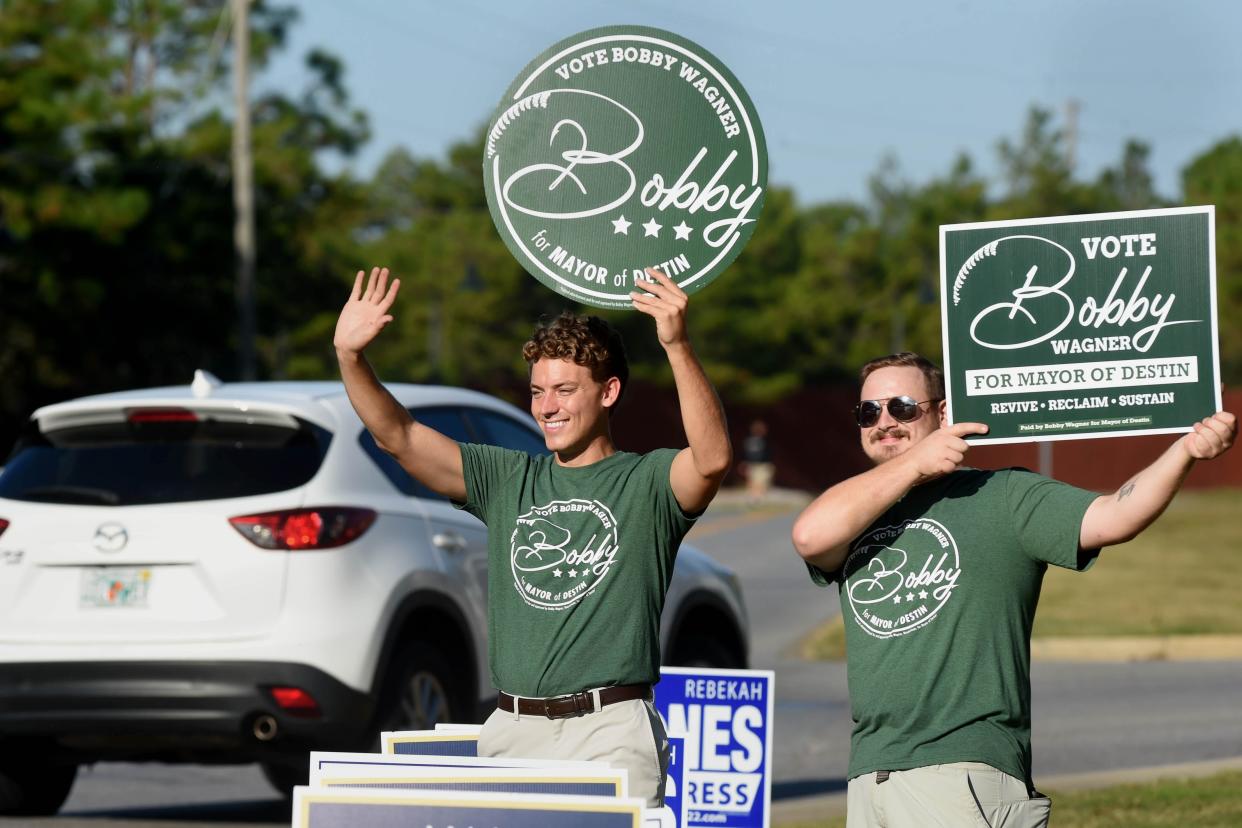 Destin mayoral candidate Bobby Wagner, left, and Joshua Cowsert wave to motorists near the voting precinct at Destin City Hall on Tuesday. Wagner ultimately won the election, defeating Rodney Braden.