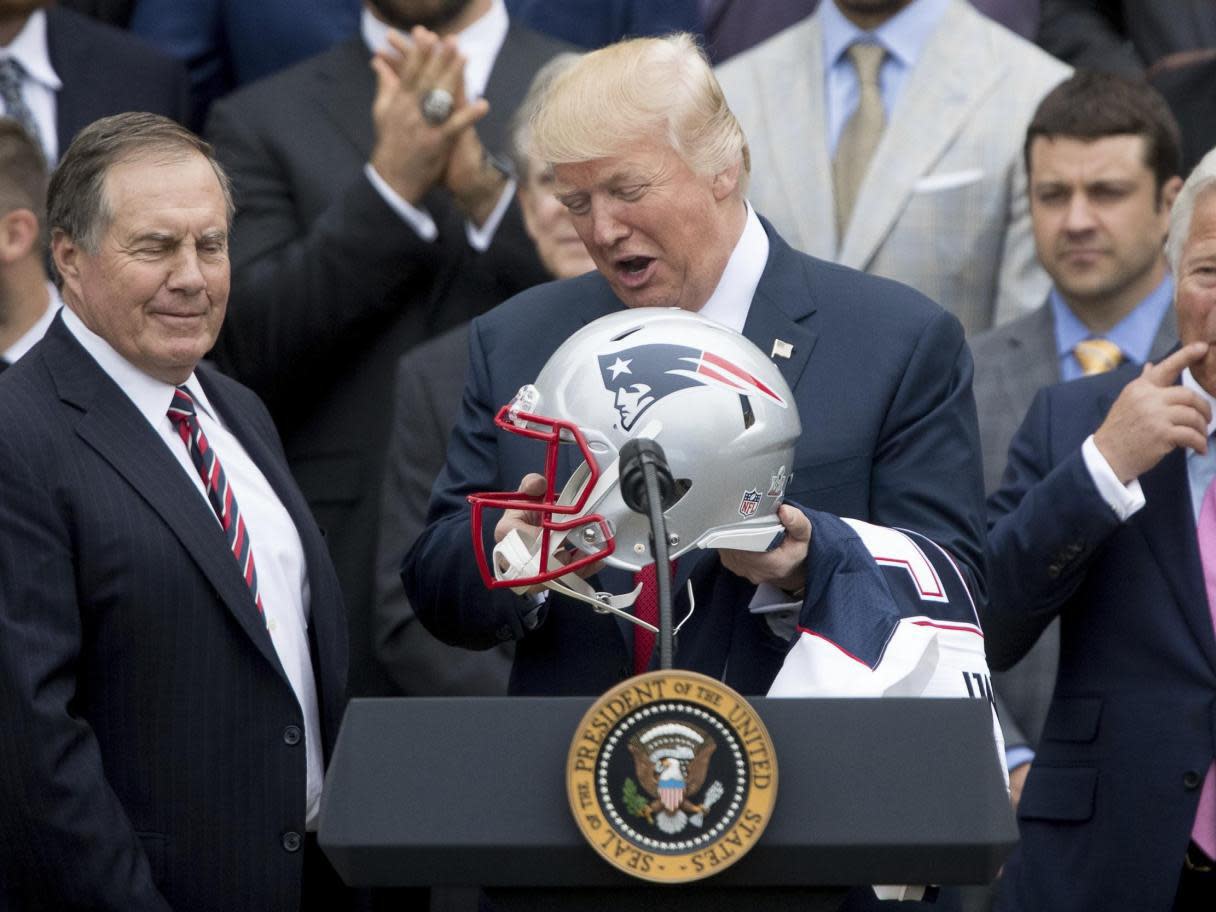 President Donald Trump holds a New England Patriots football helmet and jersey during a ceremony on the South Lawn of the White House: Associated Press