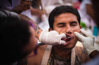 PHUKET, THAILAND - OCTOBER 05: A devotee of the Chinese shrine of Sui Boon Tong Shrine, pierces his cheeks with a sword during a procession at the Vegetarian Festival on October 5, 2011 in Phuket, Thailand. Ritual Vegetarianism in Phuket Island traces it roots back to the early 1800's. The festival begins on the first evening of the ninth lunar month and lasts for nine days. Participants in the festival perform acts of body piercing as a means of shifting evil spirits from individuals onto themselves and bring the community good luck. (Photo by Athit Perawongmetha/Getty Images)