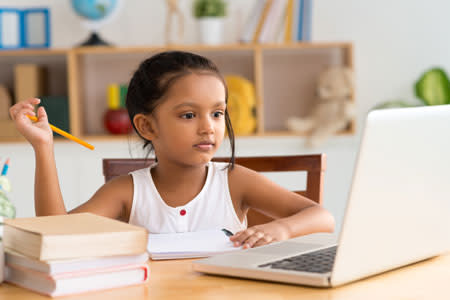 a young child in a classroom looking at a computer screen