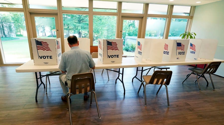 FILE – A voter sits alone at a poll kiosk to cast his vote at a Mississippi Second Congressional District Primary election precinct, June 7, 2022, in Jackson, Miss. More than 1 million voters across 43 states have switched to the Republican Party over the last year, according to voter registration data analyzed by The Associated Press.