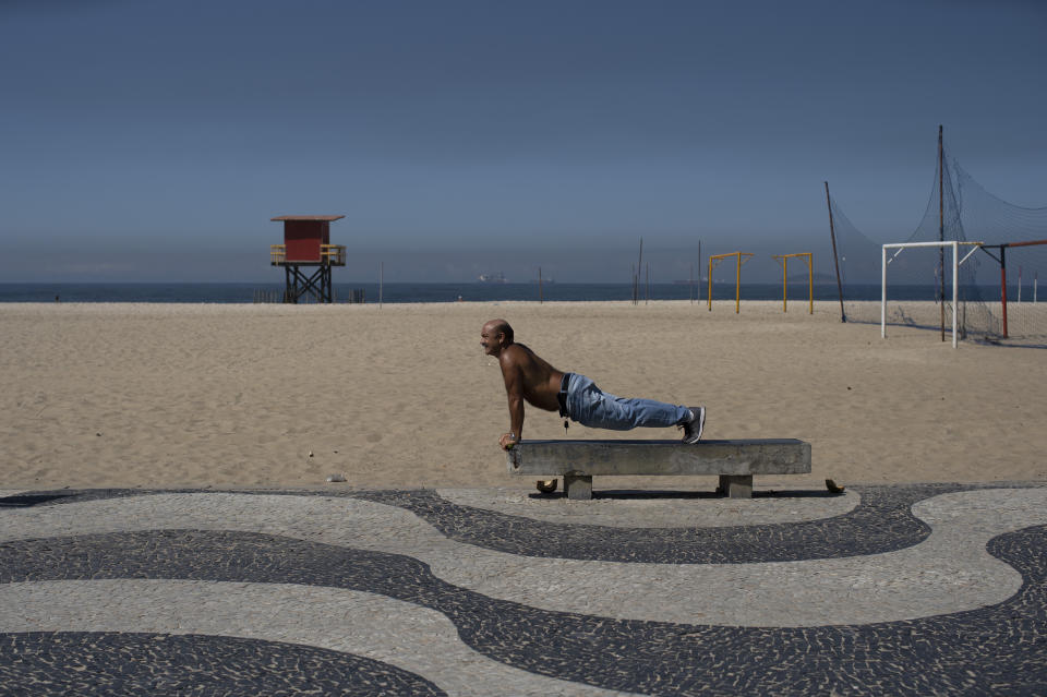 A man exercises on a bench amid the new coronavirus pandemic on Copacabana beach, Rio de Janeiro, Brazil, Wednesday, April 29, 2020. Rejection of quarantine to help contain the spread of COVID-19 is evident among the people soaking up sunshine in the beachside neighborhoods of Copacabana and Barra da Tijuca. (AP Photo/Silvia Izquierdo)