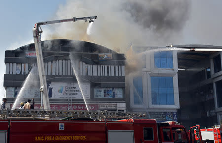 Firefighters douse a fire that broke out in a four-story commercial building in Surat, in the western state of Gujarat, India, May 24, 2019. REUTERS/Stringer