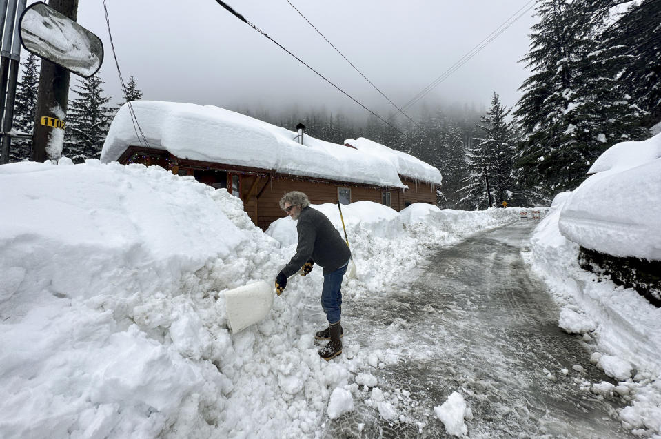 Dave Harris shovels snow near his home in Juneau, Alaska, on Wednesday, Jan. 24, 2024. The city on Wednesday closed the road that goes past his house to an area where people can access popular hiking trails due to avalanches but Harris said he feels safe where his house is located. (AP Photo/Becky Bohrer)
