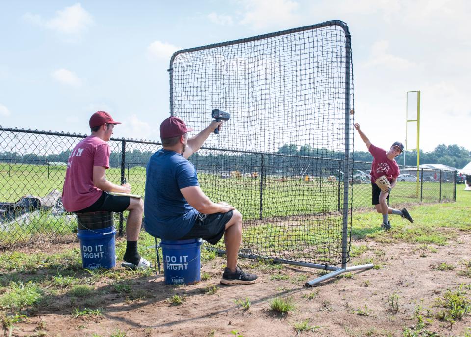 Head coach Chris Lyle, center, uses a radar gun to measure the speed of his players' throws during practice at L.E.A.D. Academy in Pace on Monday, July 11, 2022.