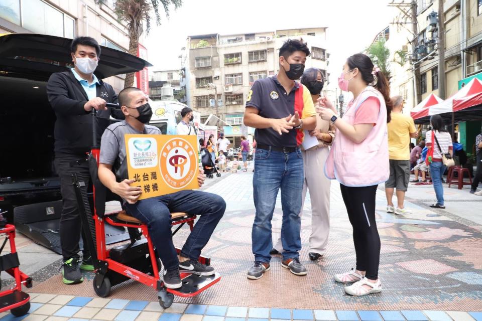 「關懷鄉親福利大車隊」為民眾解說長照福祉車和爬梯巴士的申請和使用。（新北市社會局提供）