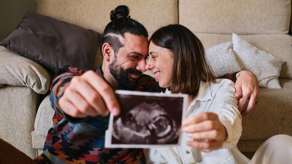 Una pareja muestra el eco de su bebé